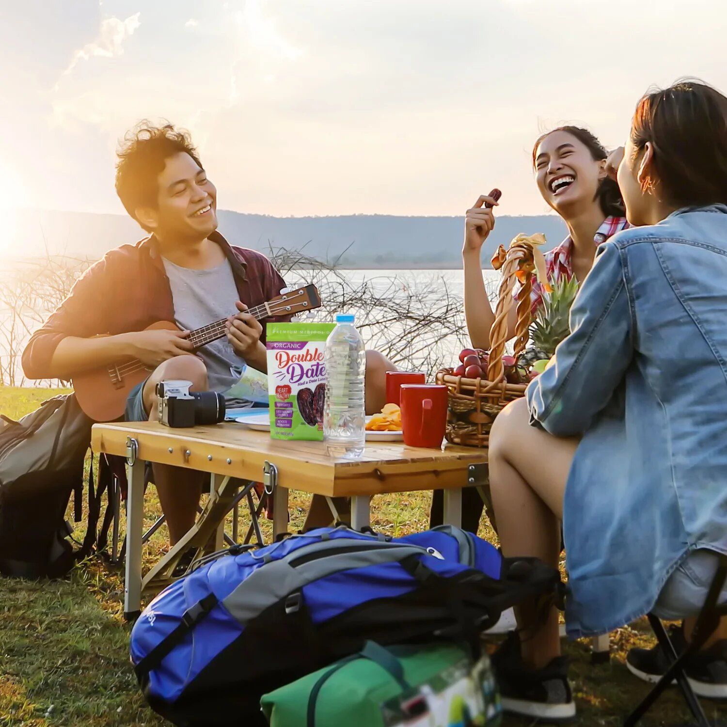 Friends sharing Double Date Medjool dates at a lakeside campsite