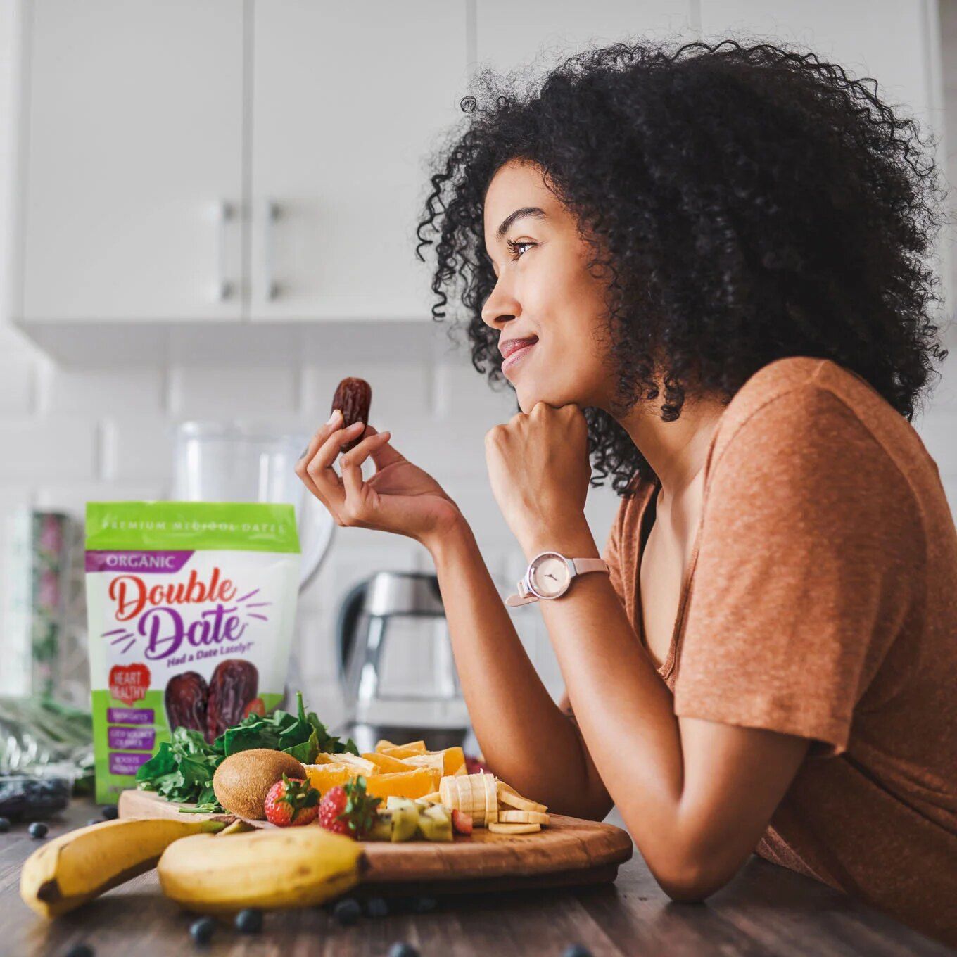Woman enjoying a Medjool date in her kitchen beside a Double Date pouch